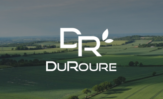 Une vue aérienne de champs agricoles vallonnés, avec le logo DuRoure en blanc (monogramme DR et nom de l'entreprise) superposé au centre de l'image.