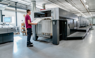 salarié en train de contrôler le format imprimé sortant de la machine offset